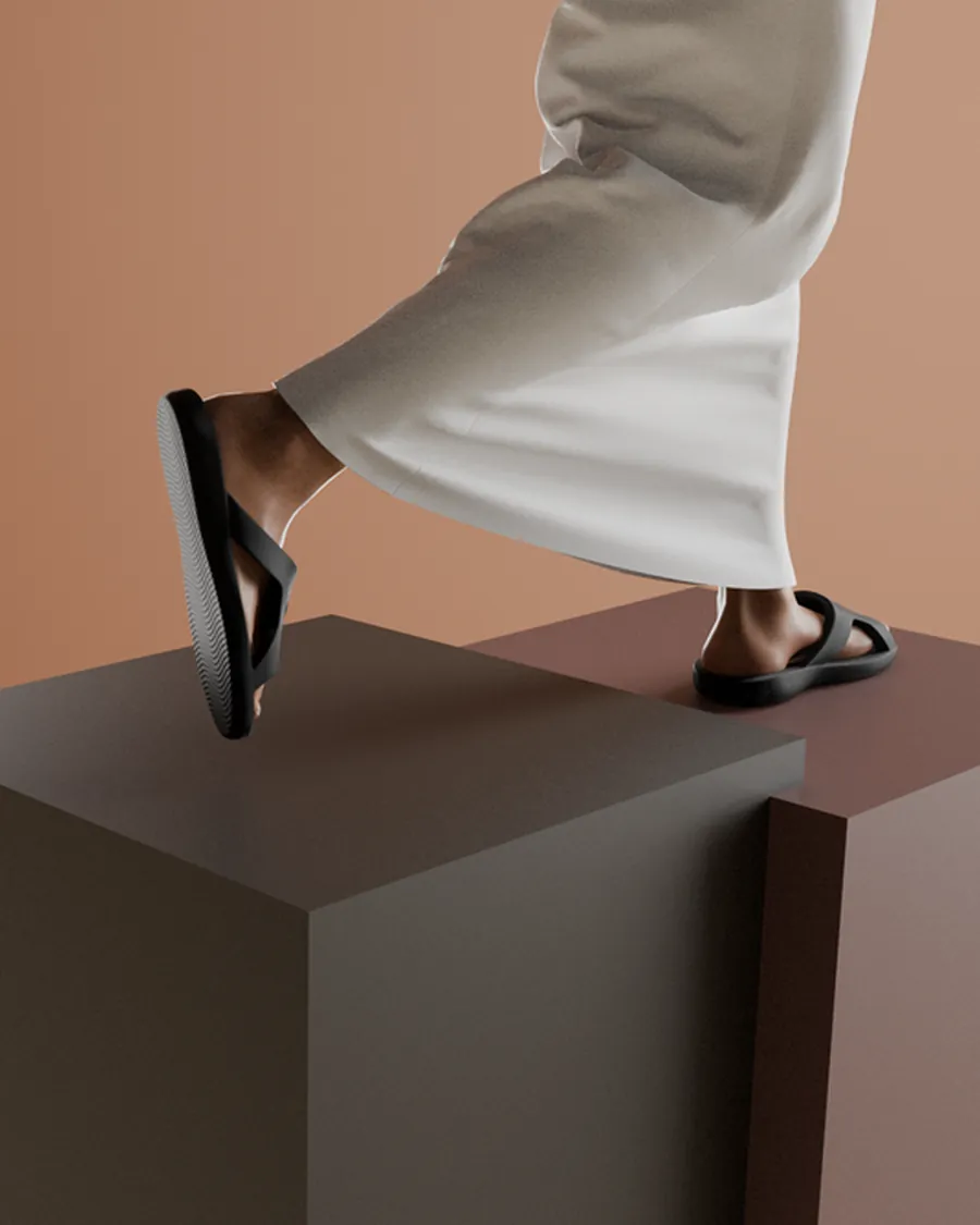 Black SandX slides worn on a stone step